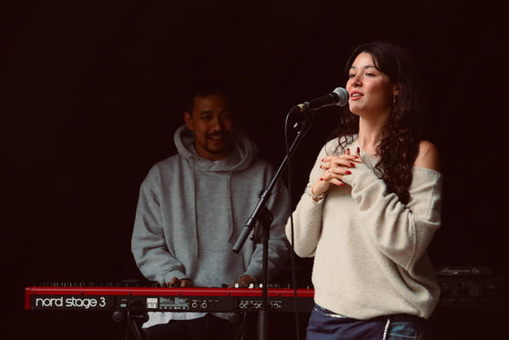 AZURE singer and songwriter performs live on stage with pianist in the background.