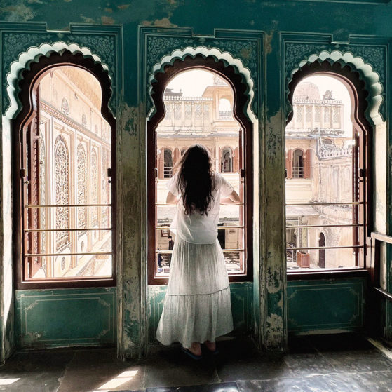 AZURE, artist stand looking our window at palace in India.